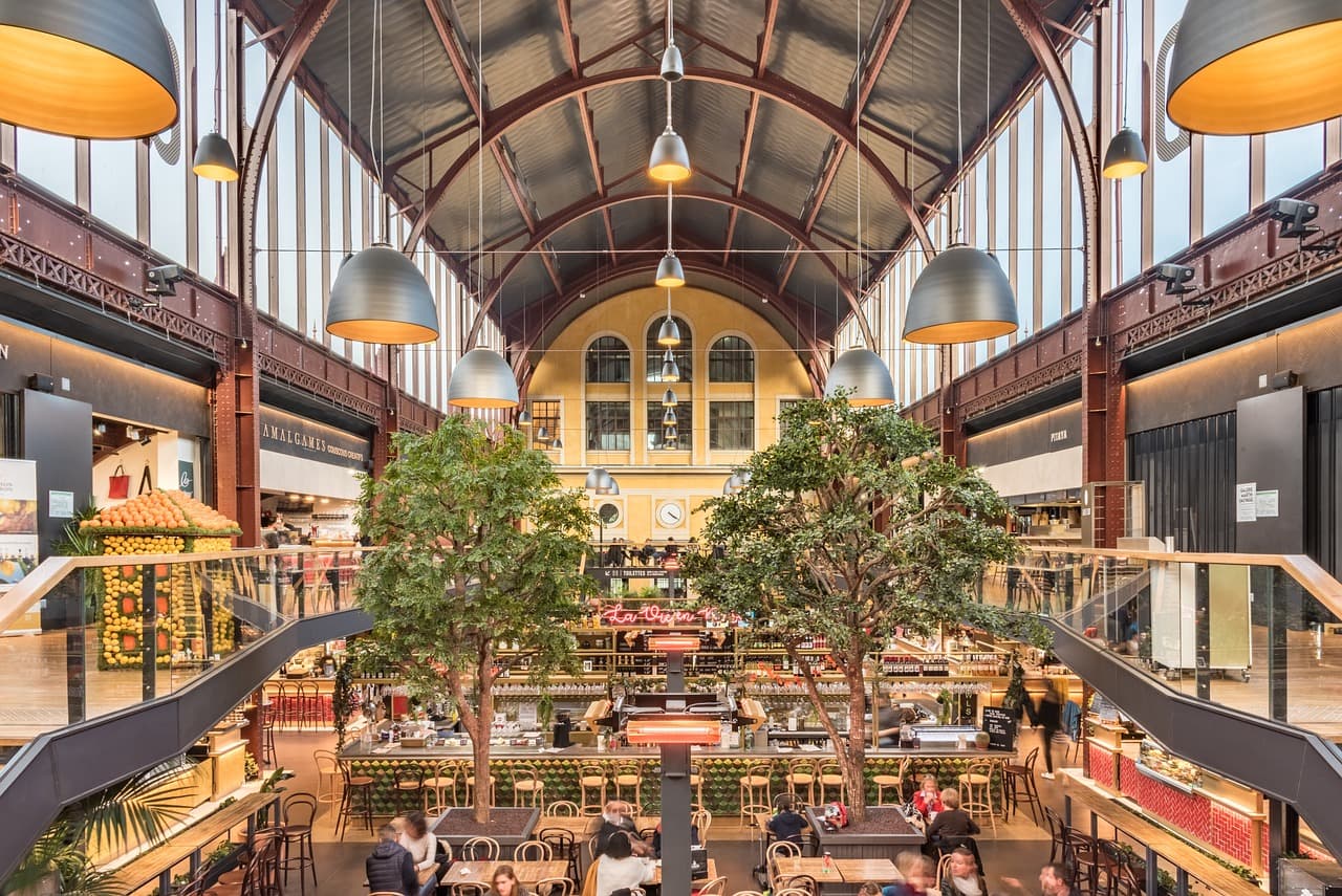 Interior view of MAR Shopping in Faro, Algarve, featuring a bustling modern atrium with dining areas and retail stores.