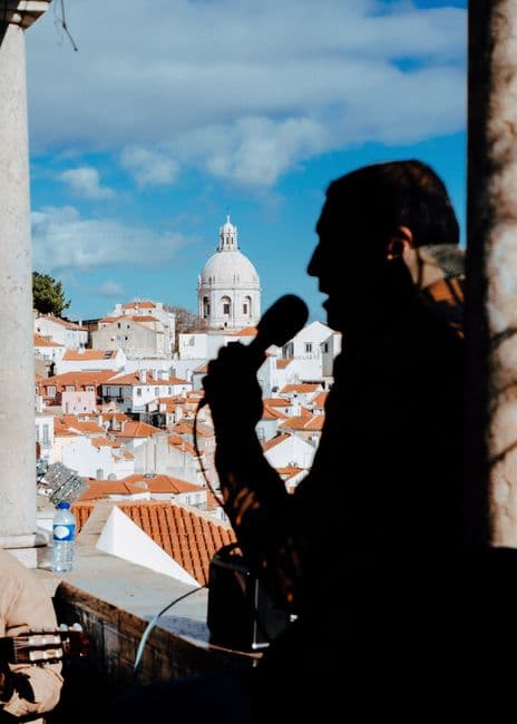 Fado singer performing with a microphone overlooking a cityscape in São Brás de Alportel, Algarve.