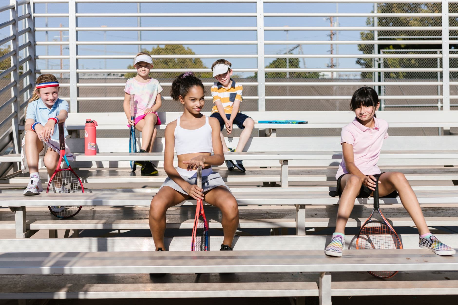 Young junior tennis players sitting on court bleachers at tennis camp in Faro, Algarve