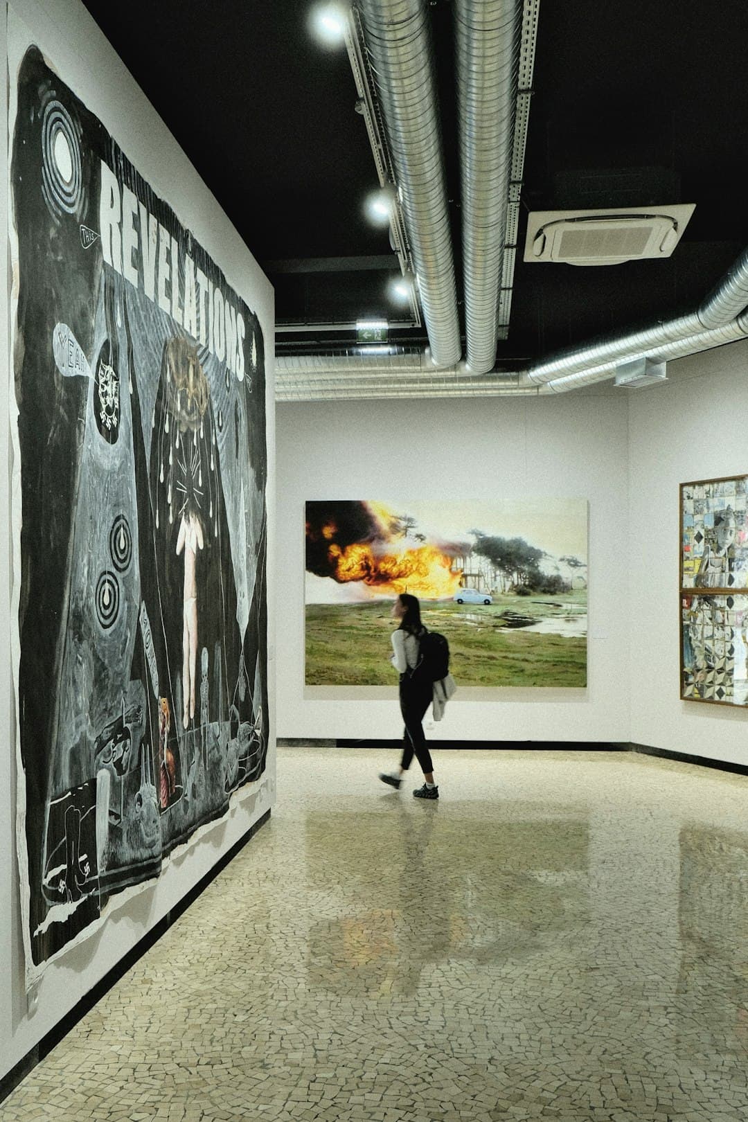 A person walking in an art gallery with paintings on the walls