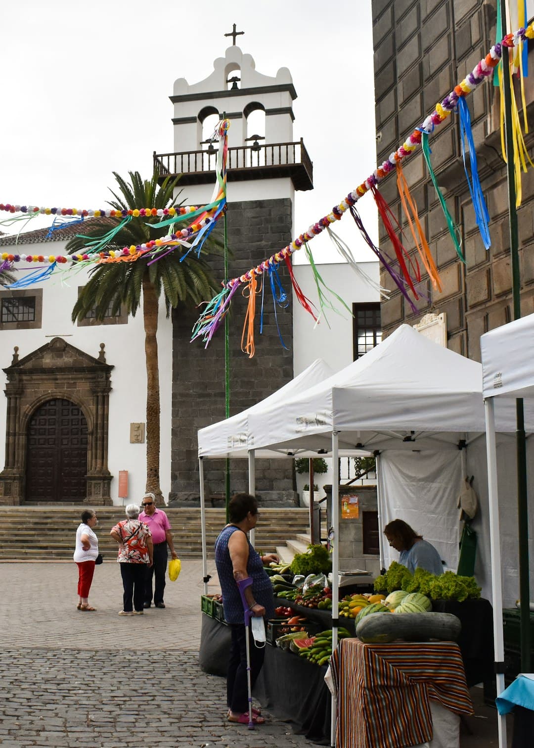 Sábados no Mercado market stalls outside a historic church with festive decorations in São Brás de Alportel, Algarve.