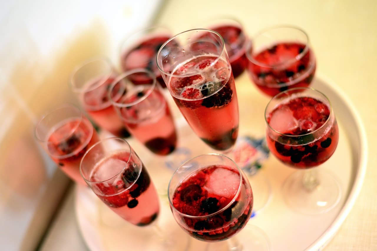 Glasses of sparkling champagne and berry cocktails on a tray at a beach club in Faro, Algarve