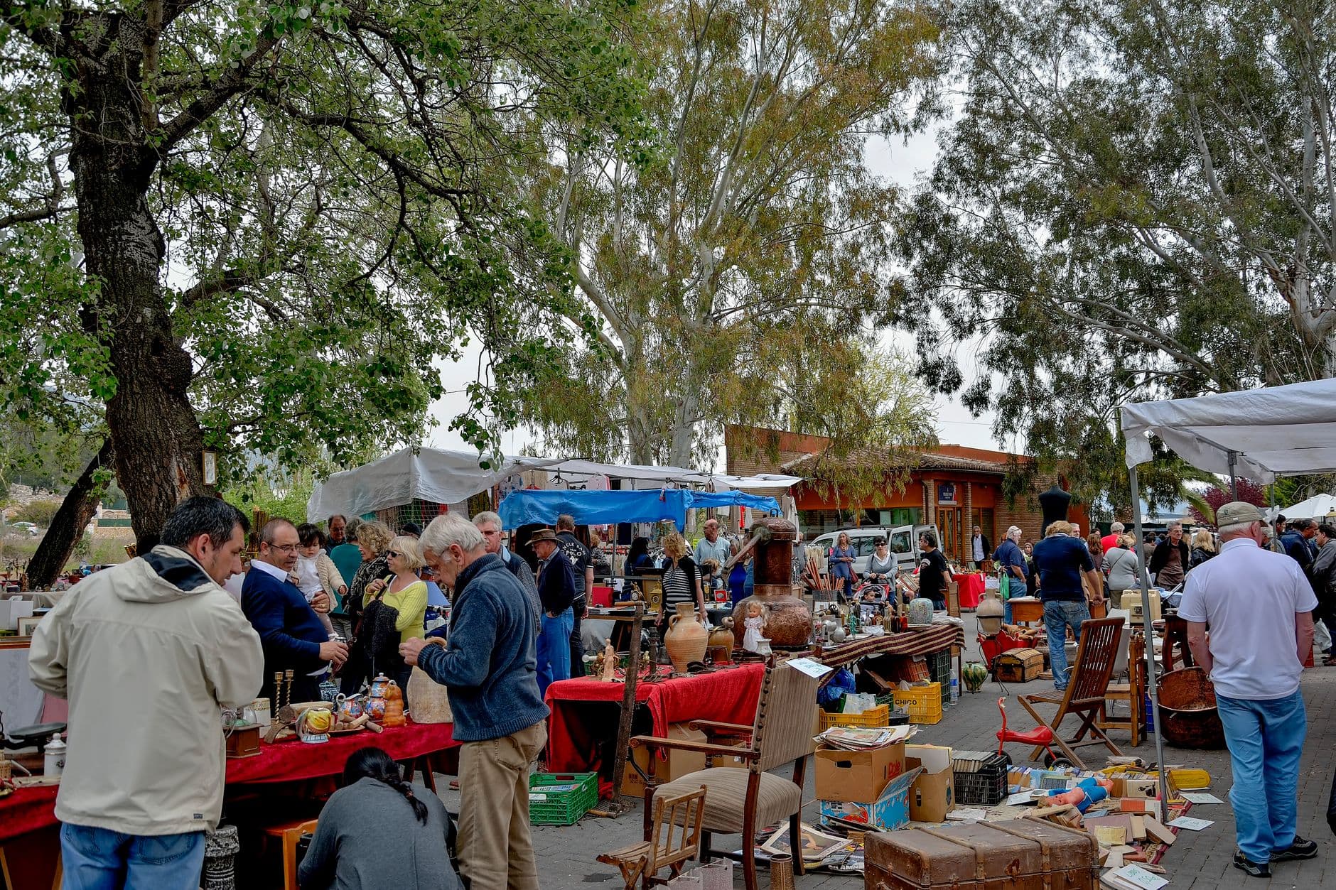 Busy outdoor flea market stalls with people browsing antiques and vintage goods in Faro, Algarve.