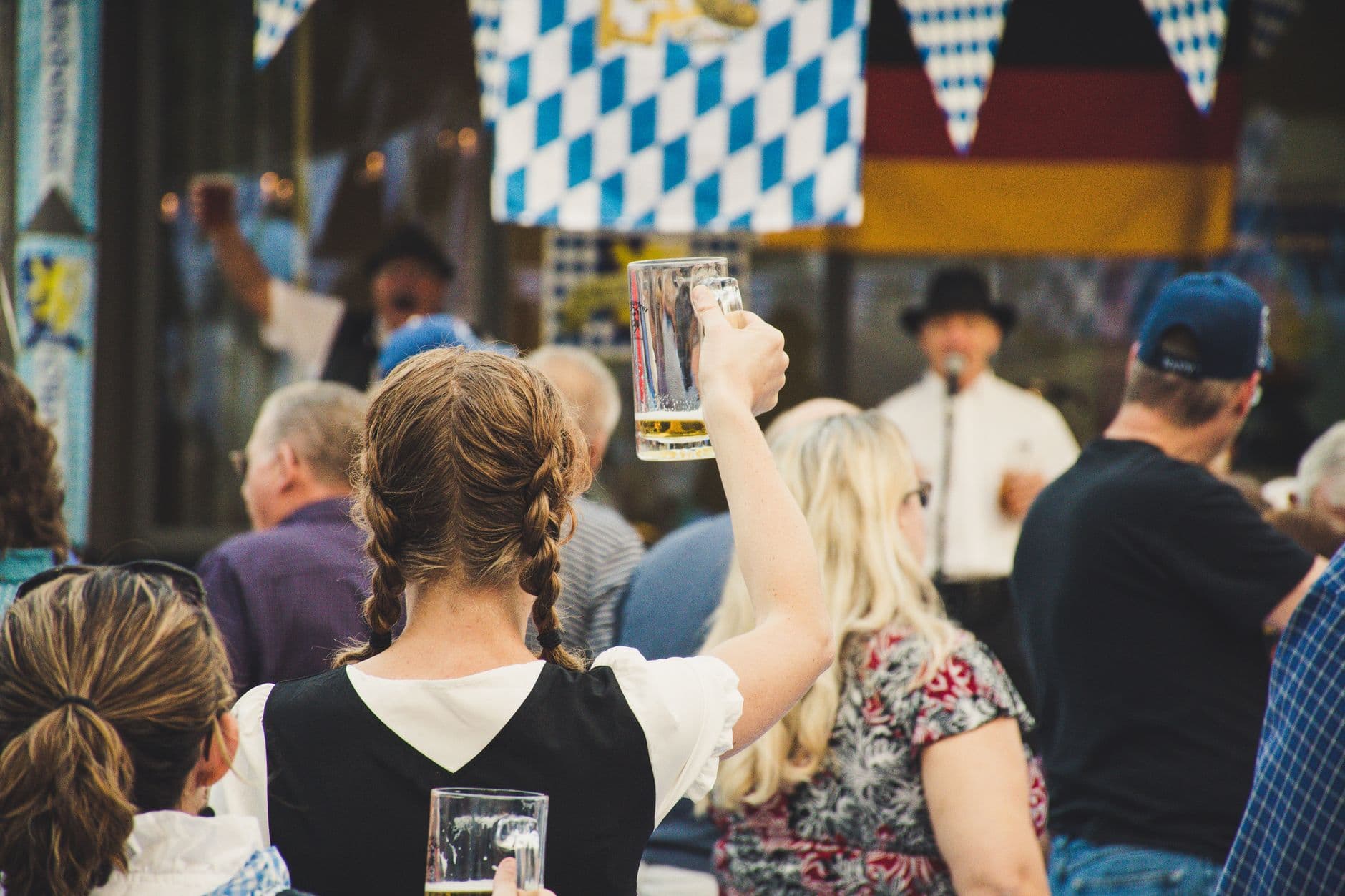 Crowd celebrating at Oktoberfest with traditional German beer stein at Vila Vita Biergarten in Faro, Algarve.