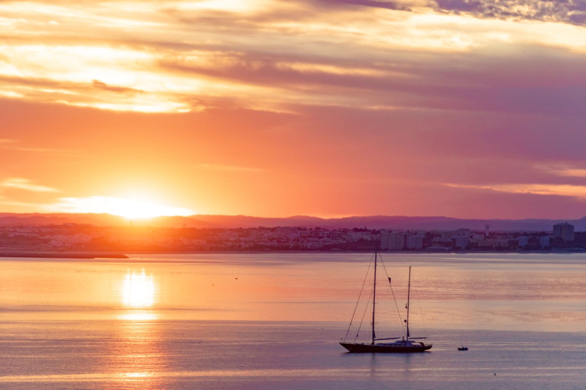Sailboat cruising during a vibrant sunset off the coast of Lagos in the Algarve, Portugal