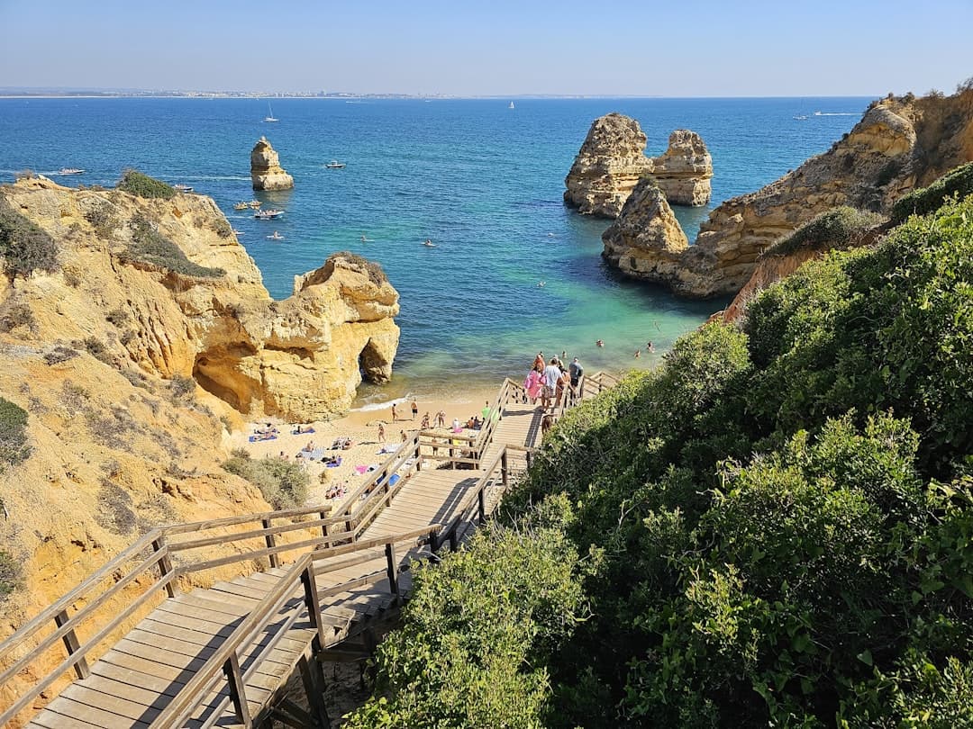 people are walking along a wooden walkway near the ocean