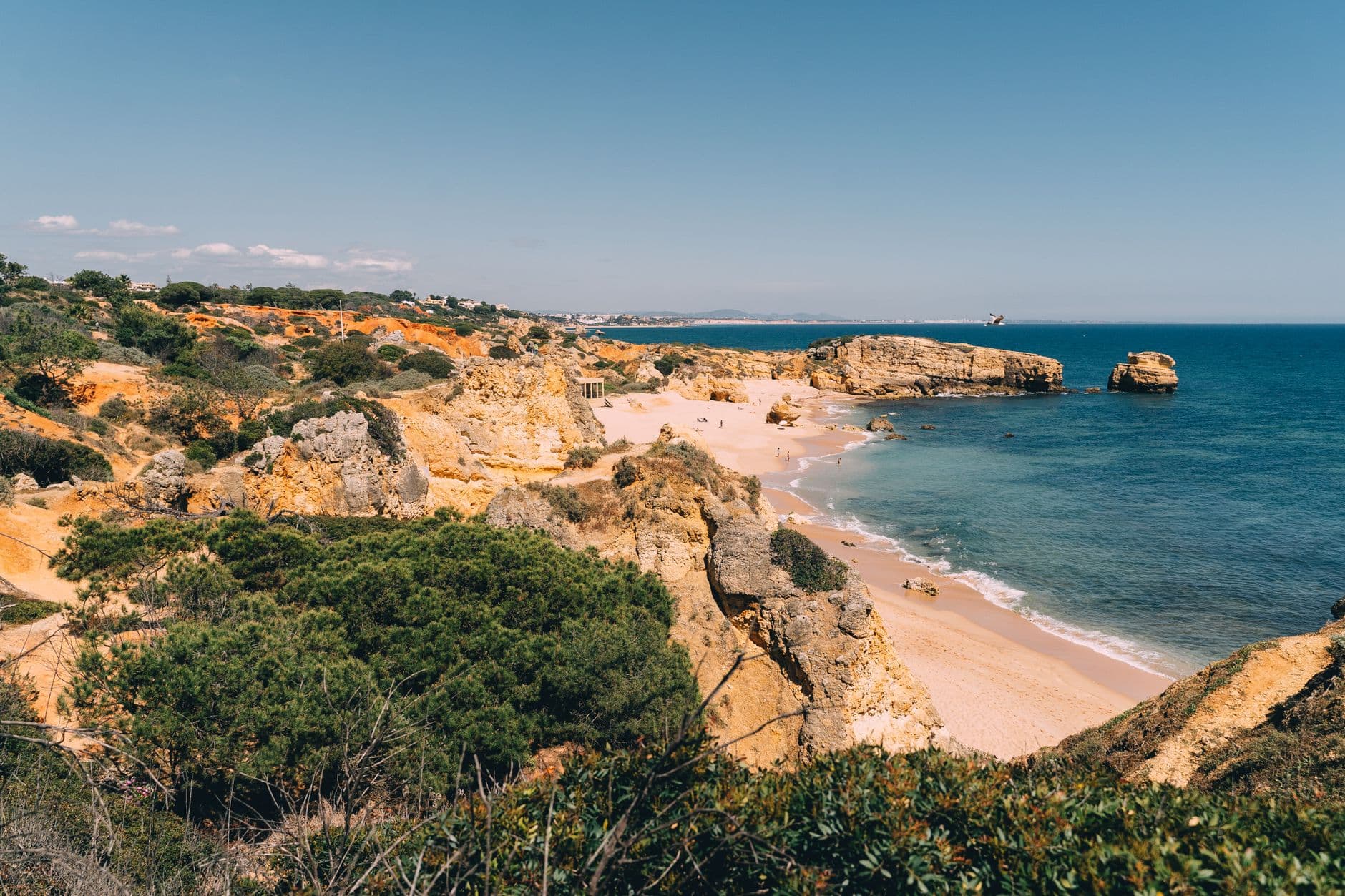 Scenic coastal view of golden cliffs, sandy beach, and blue ocean in the Algarve, Portugal