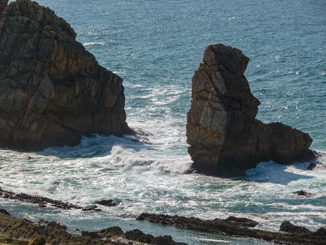 Waves crashing against jagged rock formations in the blue ocean.