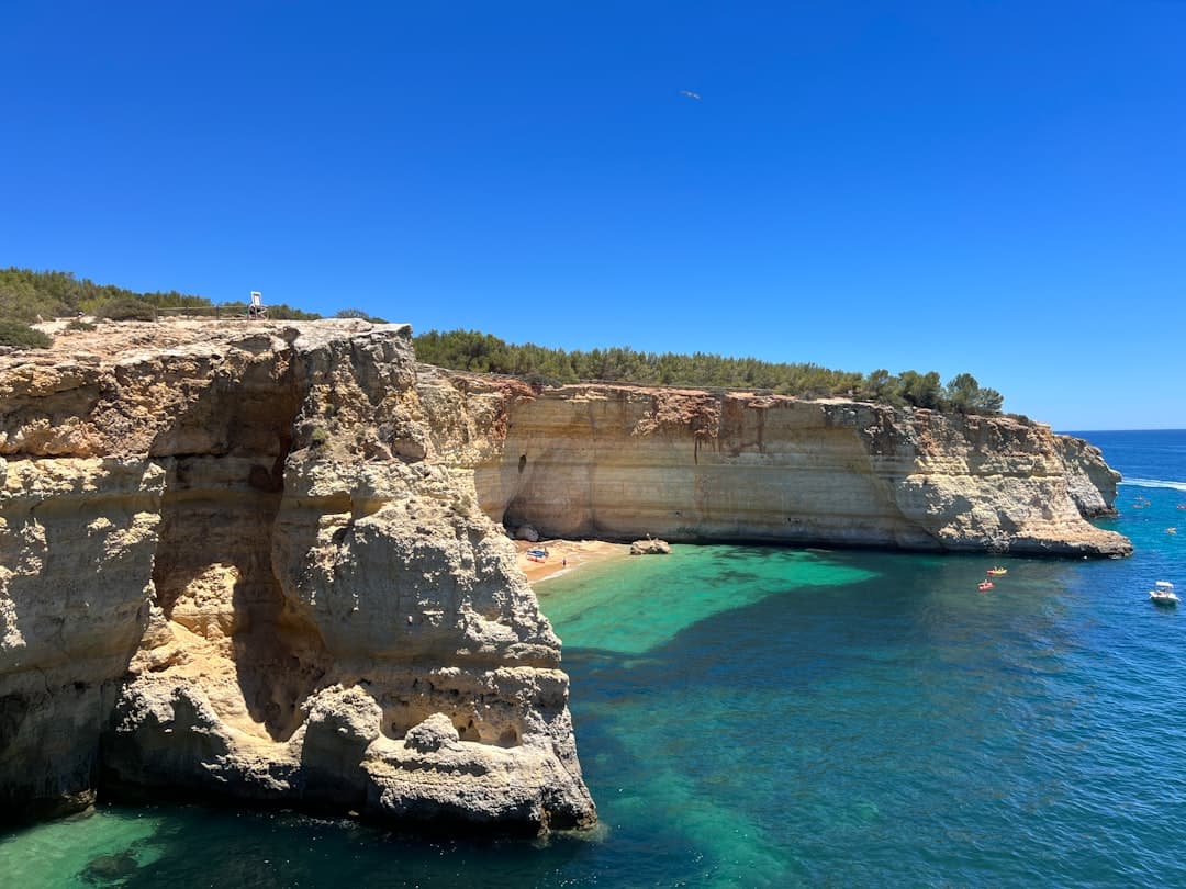 Sunny coastal cliffs, small beach, and clear blue sea